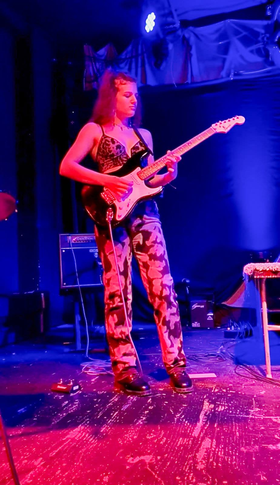 Lilla Tillo performing live on guitar under pink and blue stage lights